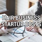 Woman analyzing hair business startup costs with a calculator and paperwork.